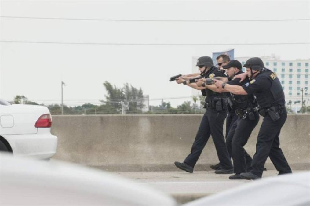 Policías armados tratan de detener a un vehículo sospechoso fuera de la terminal del aeropuerto.