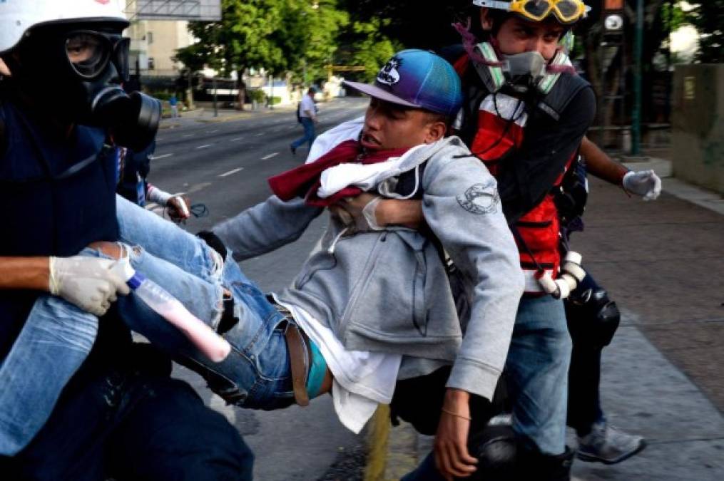 TOPSHOT - An opposition demonstrator wounded during clashes with riot police is carried away by medics during a protest against Venezuelan President Nicolas Maduro, in Caracas on June 26, 2017. <br/>A political and economic crisis in the oil-producing country has spawned often violent demonstrations by protesters demanding Maduro's resignation and new elections. The unrest has left 75 people dead since April 1. / AFP PHOTO / FEDERICO PARRA