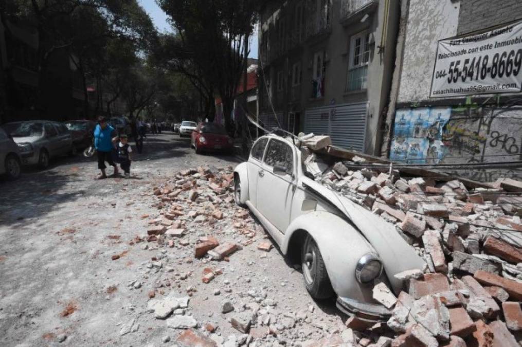 Un carro dañado y pedazos de concreto regados por la carretera.