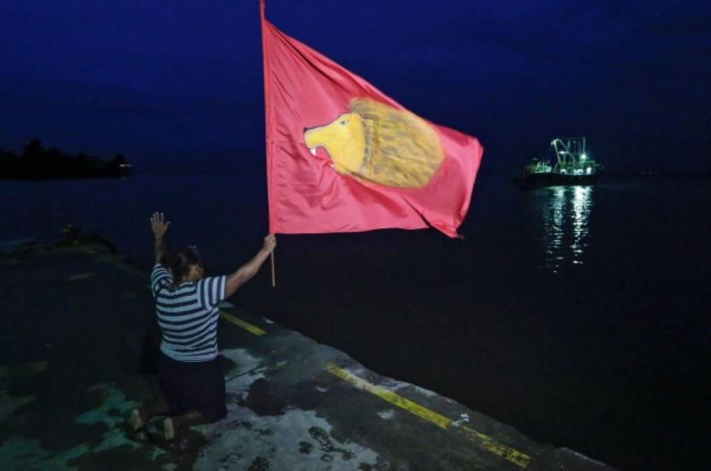 Una mujer ora con una bandera en el puerto de Bluefields, donde se prevé impacte el huracán Otto en unas horas.