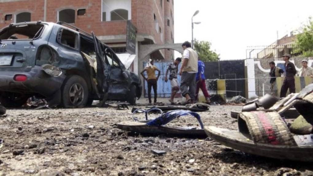 Varias personas inspeccionan el lugar de un atentado suicida en la ciudad meridional de Aden en Yemen.