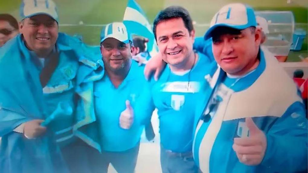 <i>En el extremo derecho, enfundado con una gorra, camiseta y chaqueta de la selección hondureña, está Miguel Arnulfo Valle, sonriente, con el dedo pulgar de su mano izquierda levantada y su brazo derecho alrededor del hombre que está junto a él, Juan Orlando Hernández, entonces presidente del Congreso de Honduras, también ataviado con parafernalia de la H, como se conoce al equipo nacional.</i>
