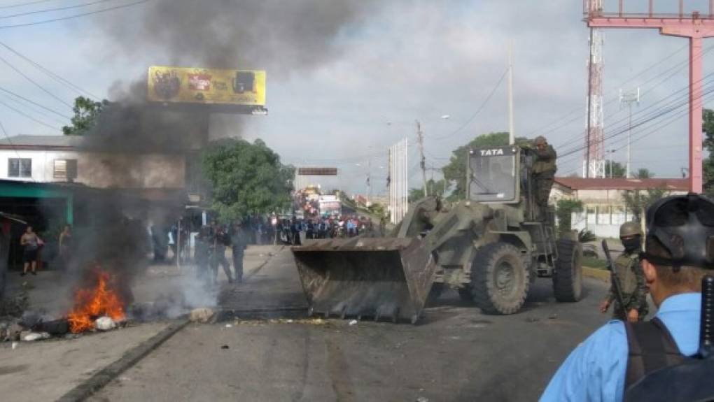 Autoridades Policiales y Militares lograron despejar los retenes ubicados en el puente La Democracia que desde el pasado lunes obstaculizaban la libre circulación en la ciudad de El Progreso, norte de Honduras. Las violentas turbas mantenían el control de la vía y no dejaban que los residentes de la Perla del Ulúa salieran o ingresaran a la ciudad. Pero no sólo no permitían la libre circulación, los manifestantes también realizaron actos vandálicos quemando varios negocios, entre ellos un autolote, saqueos a tiendas locales, quemas de postas policiales y oficinas gubernamentales, como la sucursal de Hondutel.