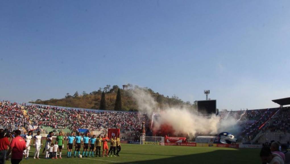 Los equipos titulares del Olimpia y Real España se forman antes del inicio del clásico y al fondo la barra del Olimpia poniendo el ambiente.