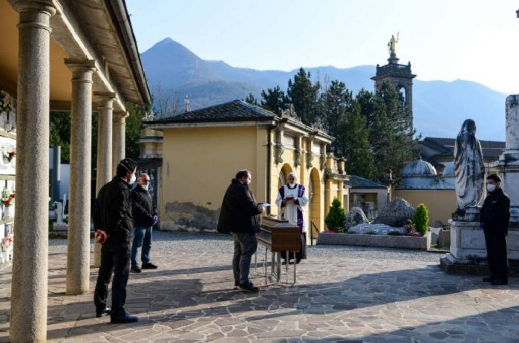 Esta imagen muestra a un hombre cerca del féretro de un familair fallecido por coronavirus, el sacerdote y los demás están a más de 2 metros de distancia.