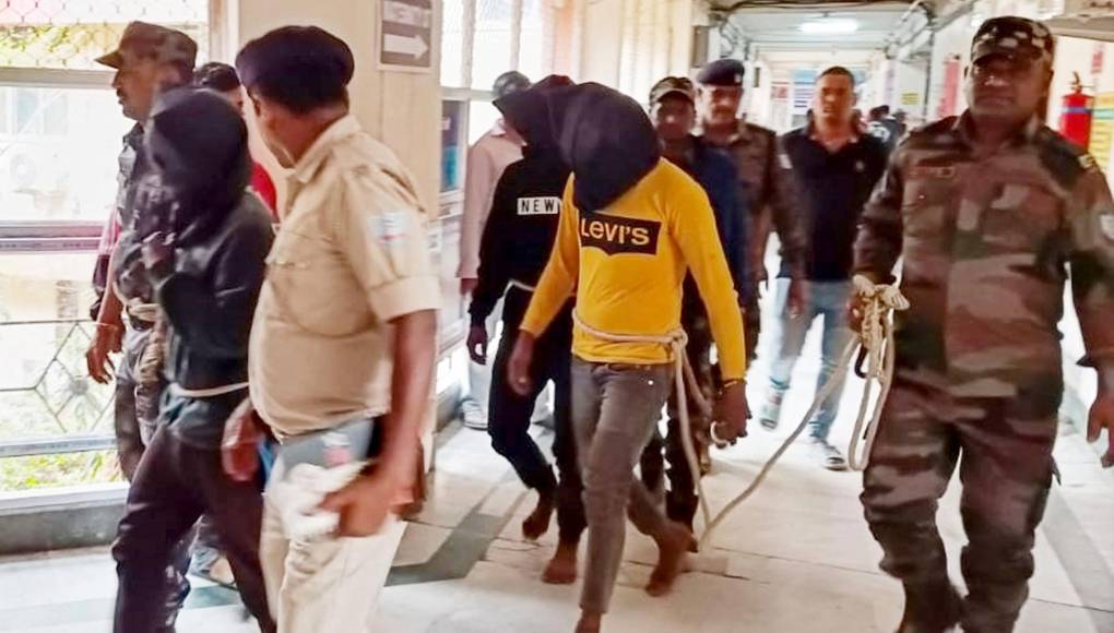 La agencia de prensa Press Trust of India (PTI) difundió imágenes de cinco sospechosos, esposados y encadenados en fila, frente a varios policías. 