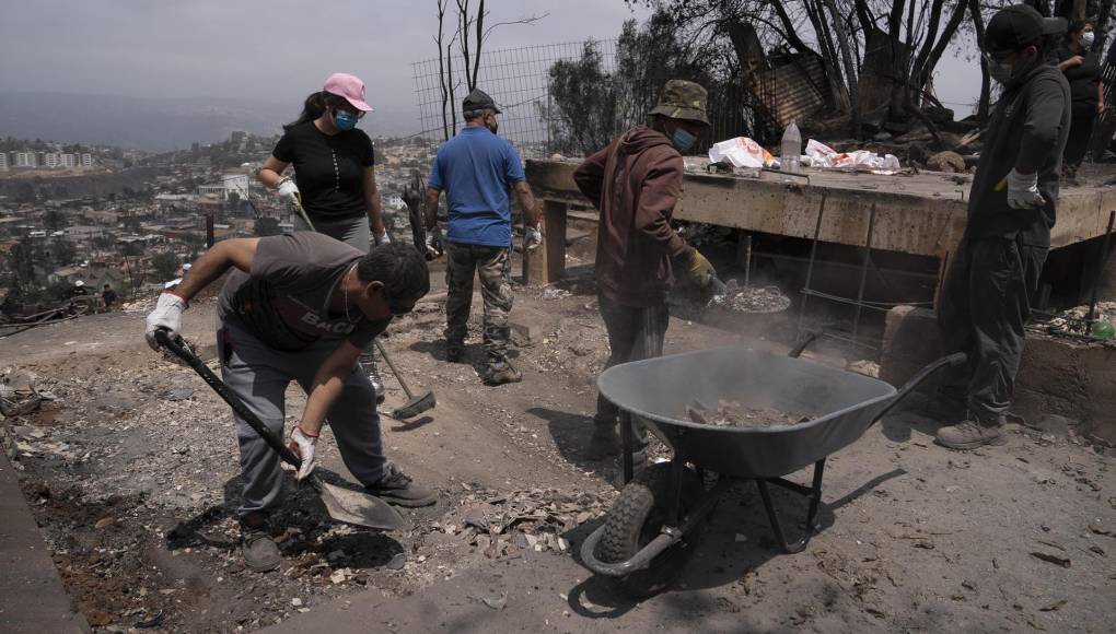  Personas ayudan a retirar escombros hoy en el sector de Achupallas, afectado por incendios forestales de Viña del Mar, Región de Valparaiso. 