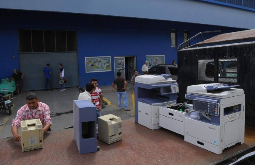 Empleados de Diario Tiempo en San Pedro Sula sacan mobiliario ante el cierre forzoso de Banco Continental.