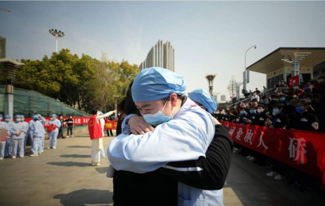 Un trabajador médico abraza a un miembro de un equipo de asistencia médica de la provincia de Jiangsu en una ceremonia que marca su partida después de ayudar con el esfuerzo de recuperación del coronavirus COVID-19, en Wuhan, en la provincia central de Hubei de China el 19 de marzo de 2020. Foto AFP