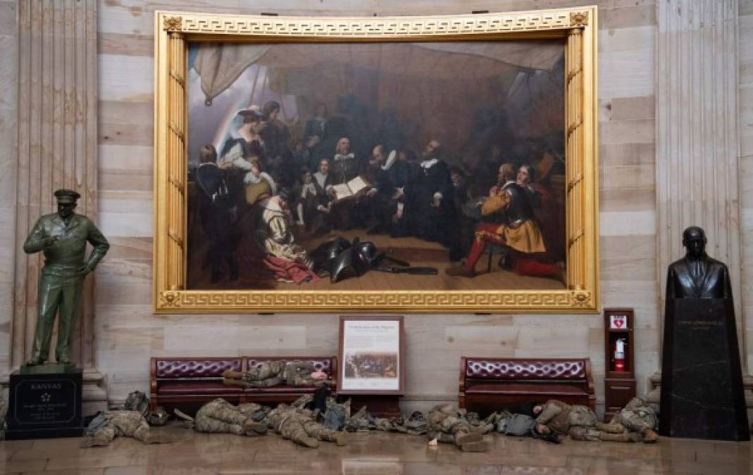 Bajo el pintoresco cuadro del desembarco de Cristóbal Colón, los militares estadounidenses despiertan para iniciar el dispositivo de seguridad a los alrededores del Capitolio. FOTO AFP