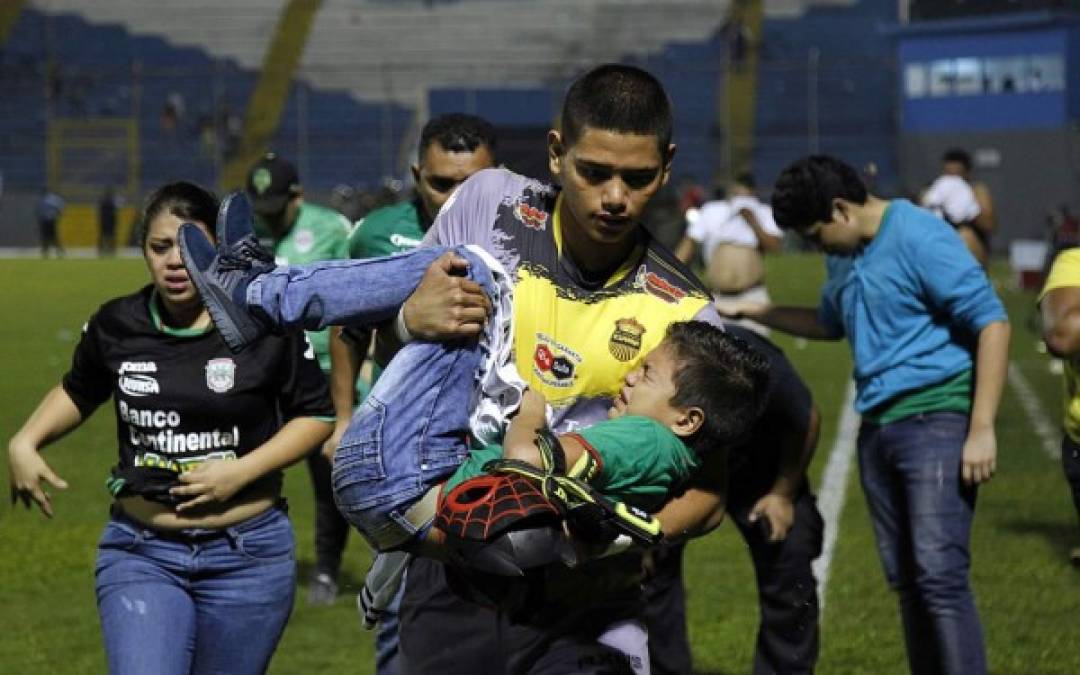 El portero suplente del Real España, Jordi Castro, ayuda a cargar a un niño alejándolo del gas de las bombas lacrimógenas.