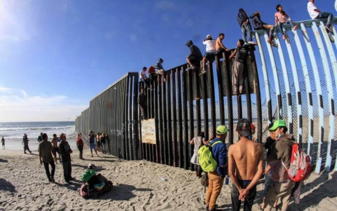 A pesar de la presencia de los agentes, una veintena de integrantes de la caravana migrante escaló los postes de metal que hacen la función de muro divisorio.<br/>