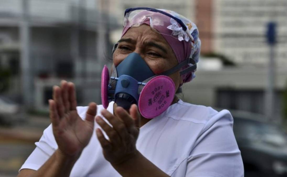 Una colega aplaude durante el funeral del enfermero caído durante la pandemia en el país. Foto AFP