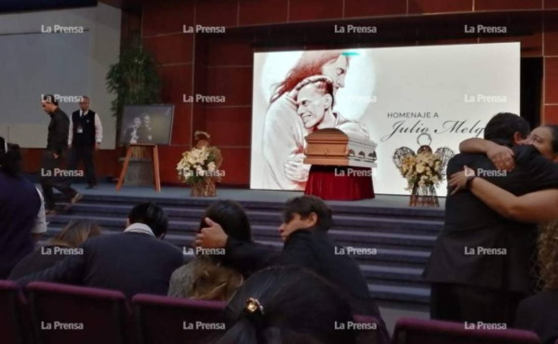 En el escenario de la iglesia luce una pancarta de Julio Melgar abrazando a Jesucristo en símbolo que este ya está en el cielo.