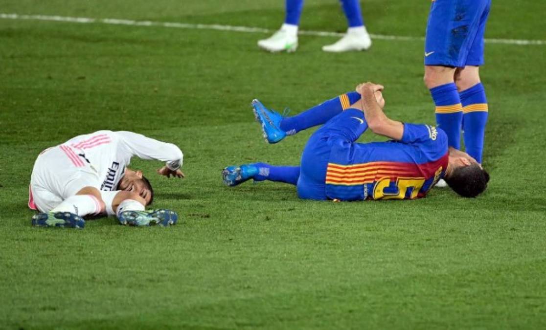 Lucas Vázquez y Sergio Busquets, dolidos en el campo tras un choque.