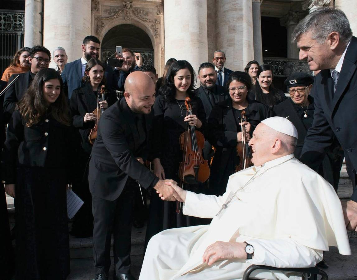 El fundador y director musical de la Orquesta Filarmónica de San Pedro Sula, Óscar Barahona, estrechando su mano con el Papa Francisco, ante la mirada de los demás talentosos integrantes de la FIL.