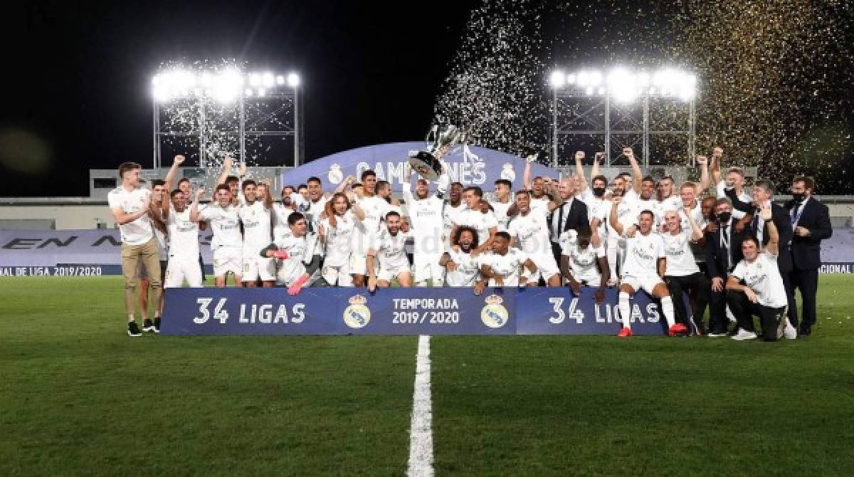 Jugadores y cuerpo técnico del Real Madrid festejando con el trofeo de campeones.