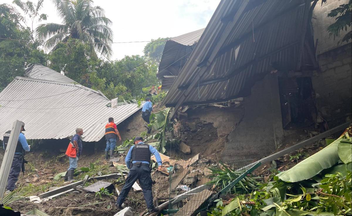 Bomberos y policías realizan labores de búsqueda y rescate en medio de los escombros dejados por un derrumbe en Choloma.