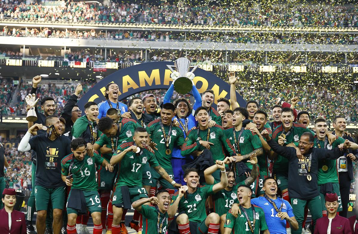 Guillermo Ochoa levantando el trofeo de la Copa Oro 2023 y sus compañeros celebrando.