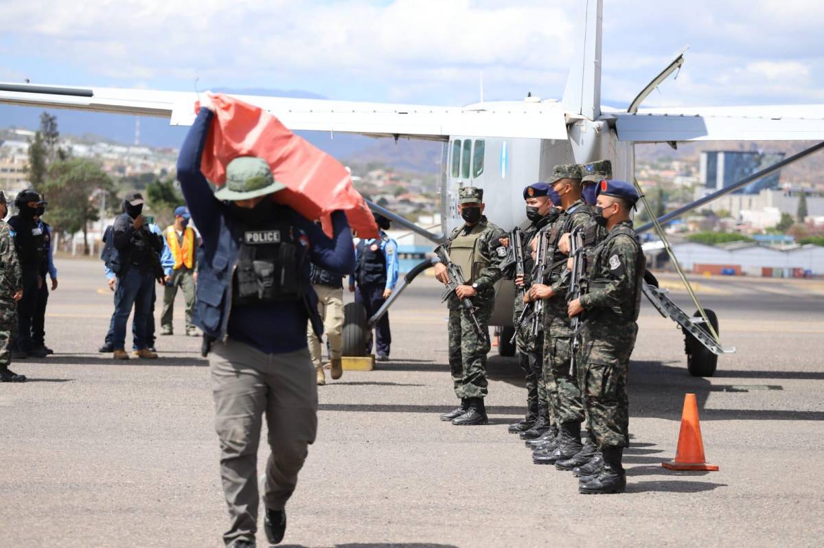 Un militar hondureño carga un saco lleno de fardos de droga decomisada el viernes en una zona del departamento insular de Islas de la Bahía, en el Caribe de Honduras.