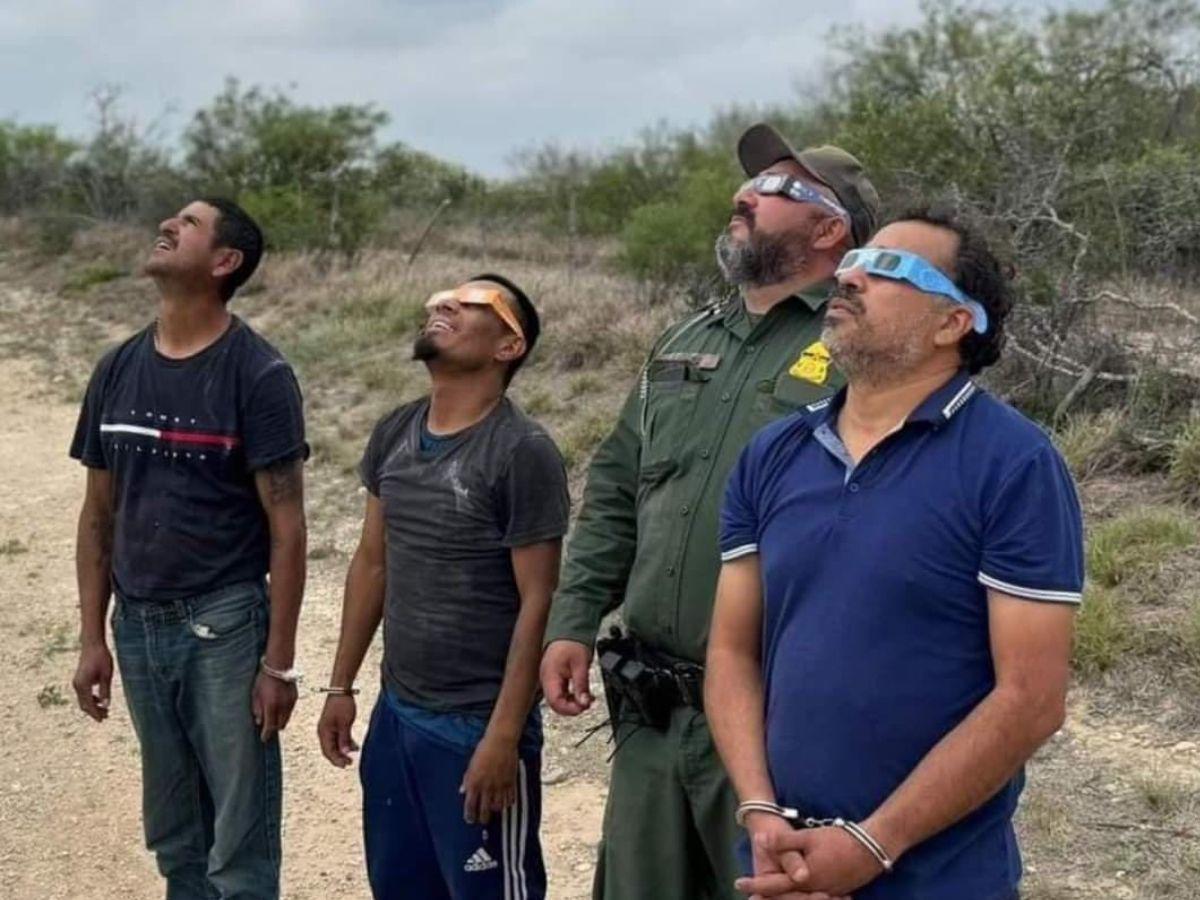 Policía fronterizo posa junto a migrantes viendo el eclipse solar en EE UU