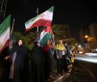 Los manifestantes ondean la bandera de Irán y las banderas palestinas mientras se reúnen en la Plaza Palestina en Teherán el 14 de abril de 2024.