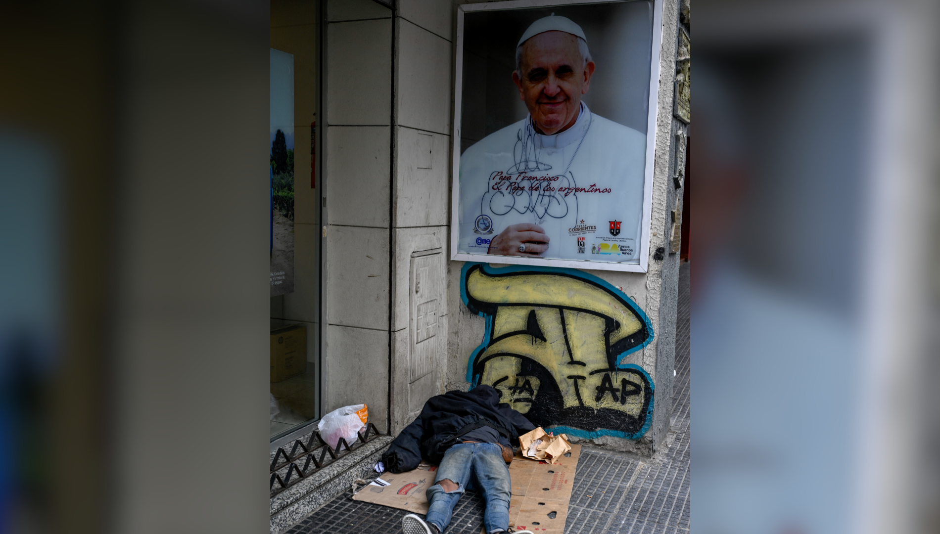 $!Una persona sin hogar duerme en una calle junto a una imagen del Papa Francisco en Buenos Aires, Argentina.