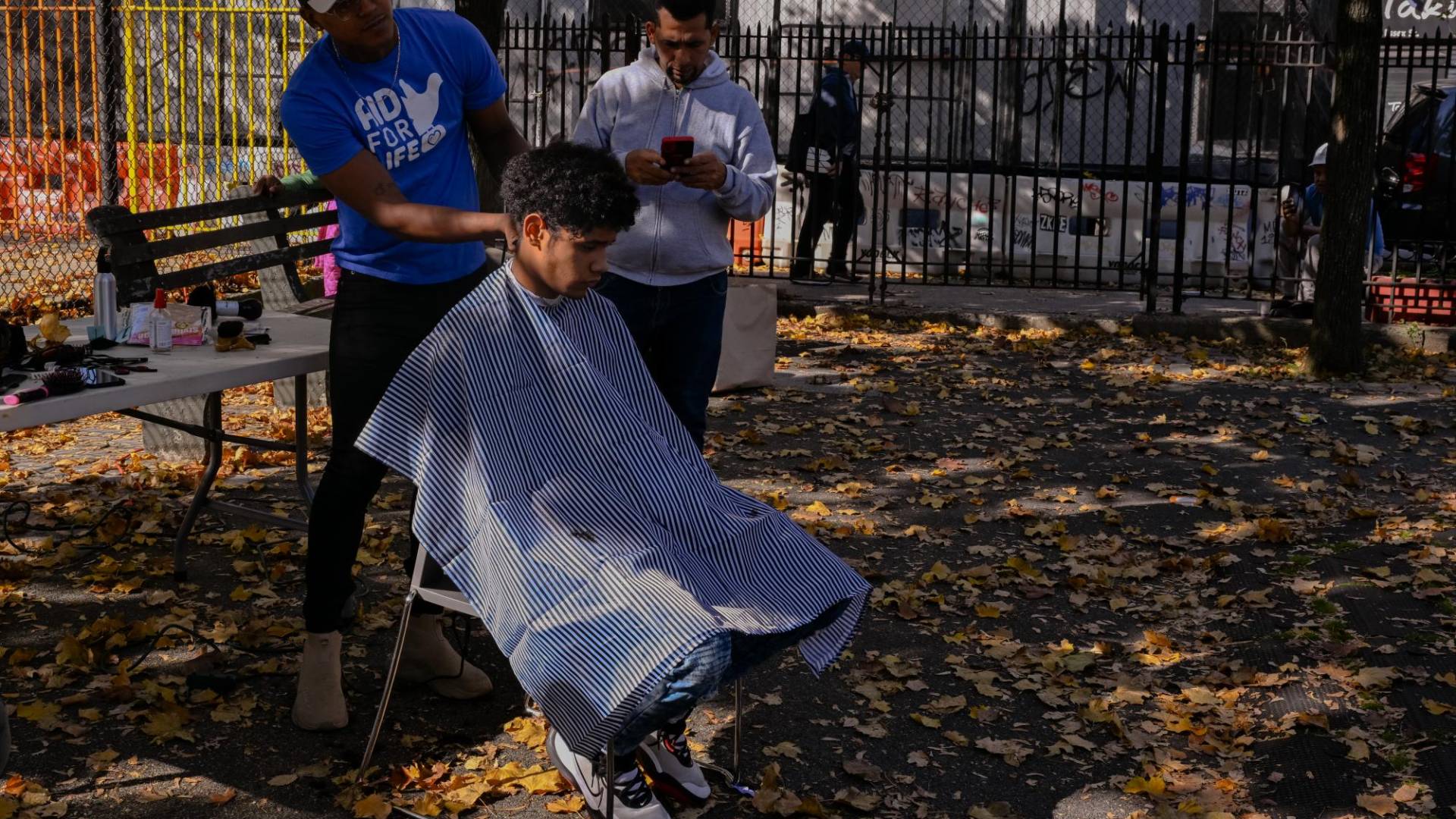 $!Roybert Suárez, un migrante que llegó a NY en septiembre, cortando el cabello a un recién llegado.