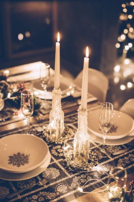 Table set up for Christmas dinner. Evening or night. Christmas tree in background.