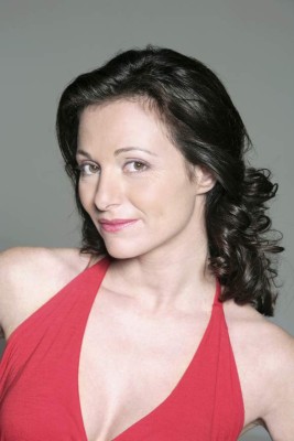 portrait on grey background of a forty years old woman in studio smiling wearing a red dress