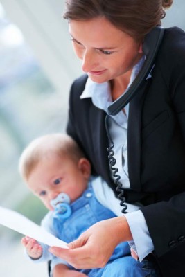 Closeup portrait of happy young business woman holding a baby and speaking on the phone