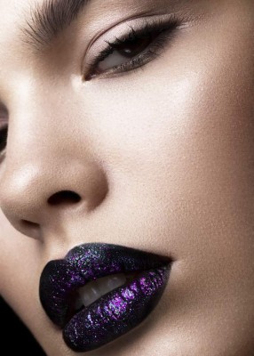 Portrait of a beautiful girl. Brilliant glossy lips closeup. Purple glitter on black lipstick.