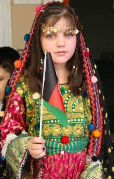 Una niña porta una bandera de su país y viste un traje tradicional para celebrar 98 años de independencia.