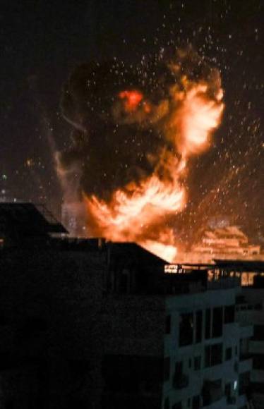 An explosion lights-up the night sky above buildings in Gaza City as Israeli forces shell the Palestinian enclave, early on May 18, 2021. - Israeli jets kept up a barrage of air strikes against the Palestinian enclave of Gaza as a week of violence that has killed more than 200 people pushed world leaders to step up mediation. (Photo by MAHMUD HAMS / AFP)