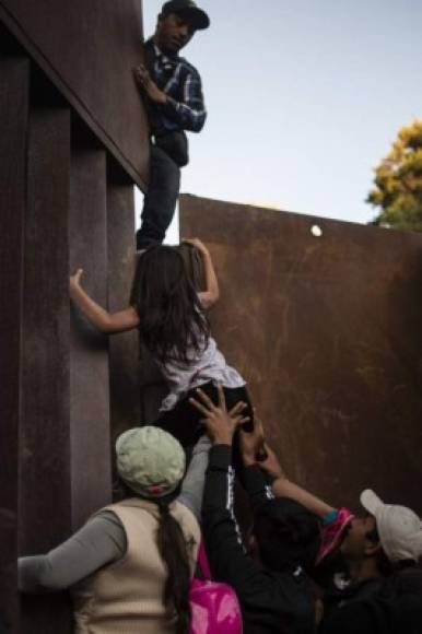 Central American migrants who have been travelling in a caravan hoping to get to the United States, climb the metal barrier separating Mexico and the US to cross from Playas de Tijuana in Mexico into the United States, on December 2, 2018. - Thousands of Central American migrants, mostly Hondurans, have trekked for over a month in the hopes of reaching the United States. (Photo by PEDRO PARDO / AFP)