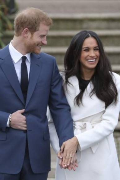 Britain's Prince Harry stands with his fiancée US actress Meghan Markle as she shows off her engagement ring whilst they pose for a photograph in the Sunken Garden at Kensington Palace in west London on November 27, 2017, following the announcement of their engagement.<br/>Britain's Prince Harry will marry his US actress girlfriend Meghan Markle early next year after the couple became engaged earlier this month, Clarence House announced on Monday. / AFP PHOTO / Daniel LEAL-OLIVAS