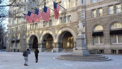 Dos turistas se hacen fotos ante la fachada principal del lujoso hotel de Donald Trump en el centro de Washington. EFE/Archivo