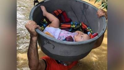 En la imagen se ve a la bebé de tan solo meses en una tina mientras es rescatada de las inundaciones.