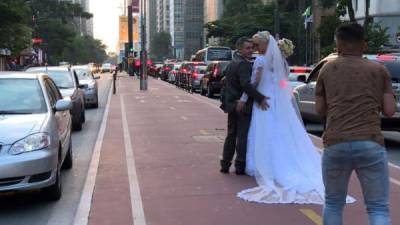 Los transeúntes los felicitan y los carros tocan el claxon mientras Ademir y Galucia posan para las fotos vestidos de novios en la icónica avenida Paulista. Foto. AFP