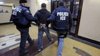 FILE- In this March 3, 2015 photo, Immigration and Customs Enforcement officers escort an arrestee in an apartment building, in the Bronx borough of New York, during a series of early-morning raids. New York City leaders are trying to strike a balance between purging dangerous criminals and protecting some of its roughly 500,000 undocumented immigrants. (AP Photo/Richard Drew, File)