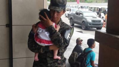 Una policía militar carga a la bebé mientras se investiga si realmente fue entregada por su madre o robada.