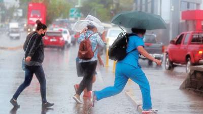 Hondureños caminando debajo de lluvia en San Pedro Sula.