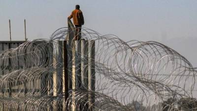 Una persona burla las alambradas de acero en Tijuana (México). EFE