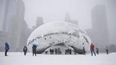 La gente camina en la puerta de La Puerta de las Nubes 'The Bean' durante una tormenta de nieve en el Parque del Milenio en Chicago, Illinois.