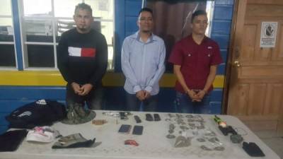 Los tres detenidos junto con lo decomisado en el momento de ser presentado ante las autoridades.