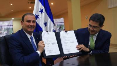 El presidente del Cohep, Juan Carlos Sikaffy sostiene junto al presidente Hernández el decreto de reforma firmado.