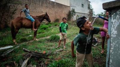 Cuatro menores en los bajos de Sao Paulo, Brasil se las ingenian para refrescarse ante las altas temperaturas.