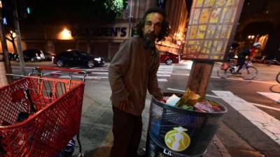 Un 'sin techo' rebusca en la basura en el barrio de Skid Row.