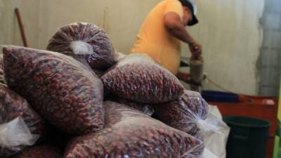 Un comerciante del mercado Dandy en San Pedro Sula llena bolsas de 15 libras de frijoles para vender.