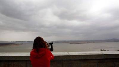 Una mujer observa hoy el condado de Gaepung-gun, en el lado norcoreano de la Zona Desmilitarizada (DMZ), desde un telescopio del observatorio de Odusan en Paju (Corea del Sur). EFE